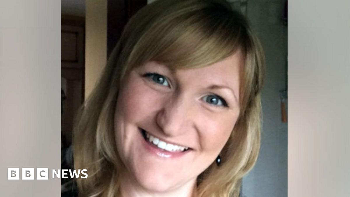A photo of Karen Booth, smiling broadly with her head tilted. She has blonde hair with a sweeping fringe and the image is closely cropped showing her face and neck.