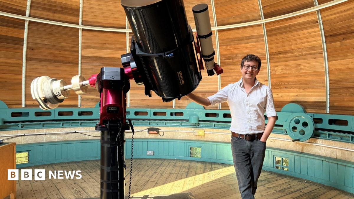Photo: bbc.co.uk Dr Matt Bothwell standing next to a telescope. He is smiling and wearing a white shirt and black jeans. He is resting his