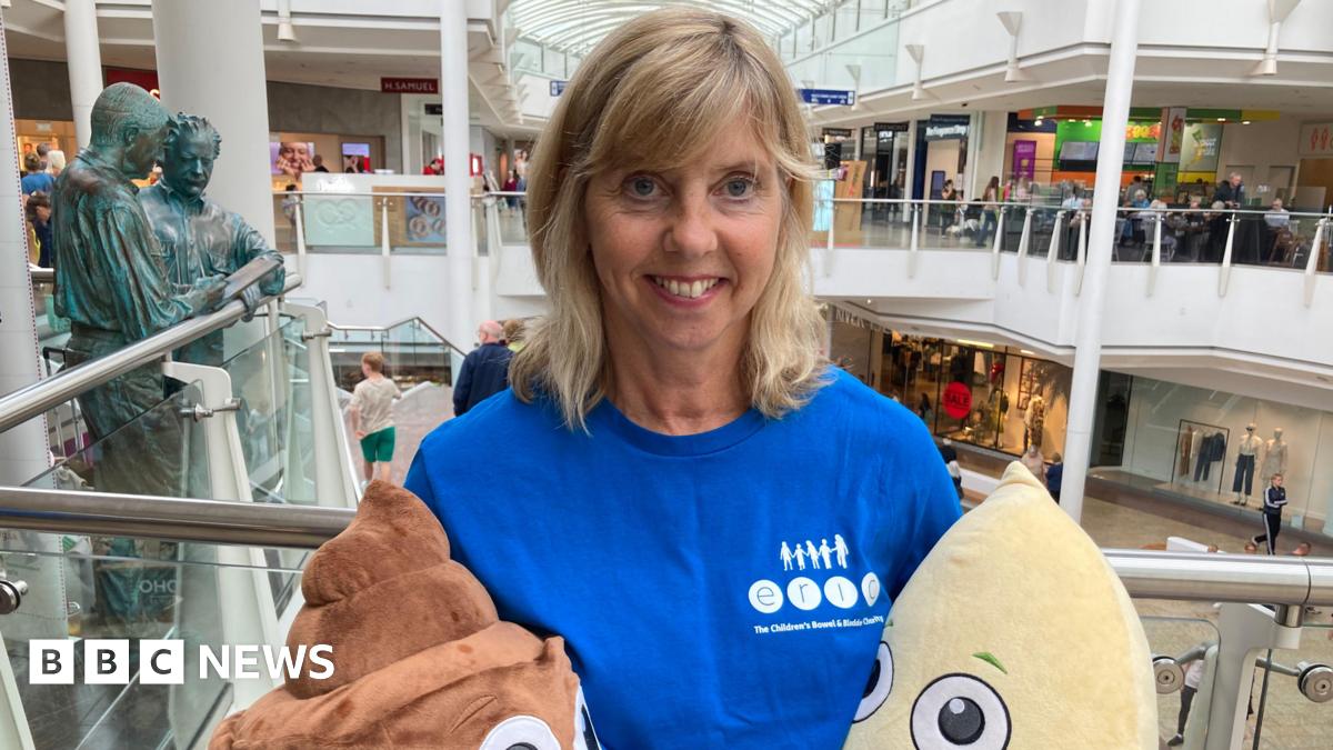 Juliette Rayner in a shopping centre, wearing a bright blue t-shirt with the ERIC logo on the front. She holds the charity's mascots, soft toys Poo and Wee in each hand, and is smiling at the camera. 