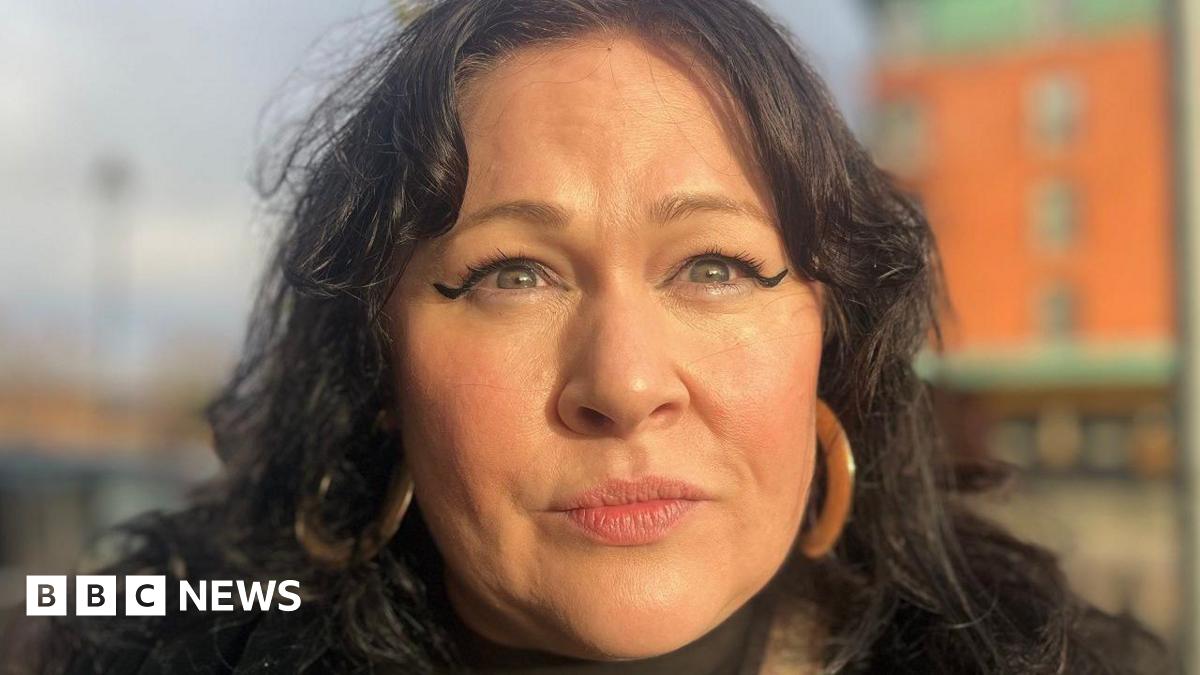 Sara Morrison has long dark hair parted in the middle and is wearing large hoop ear-rings