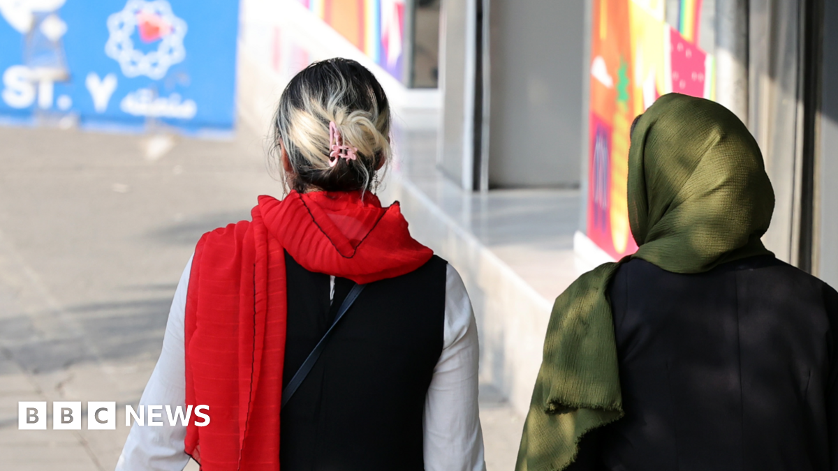 An Iranian woman (l) without a mandatory headscarf, or hijab, walks in a street in Tehran, Iran next to a woman wearing a headscarf on15 September 2024