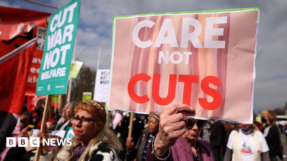 Protesters demonstrate against disability and welfare cuts during the announcement of the Spring Statement outside Parliament in London in March. They hold up placards reading: "Care not cuts".