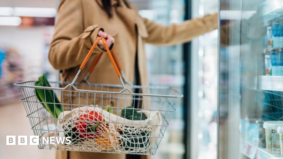 Shopper holding shopping basket in supermarket 