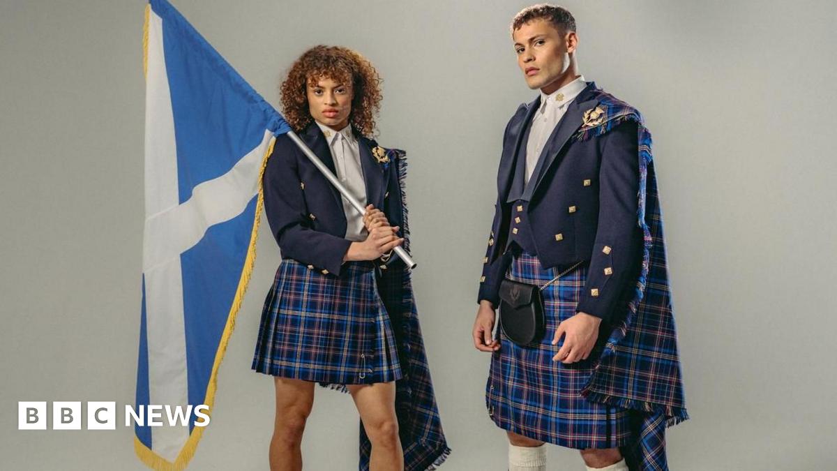 A male and female model in the Team Scotland uniform - blue tartan kilts and blue jackets. The female model is holding a saltire over her shoulders