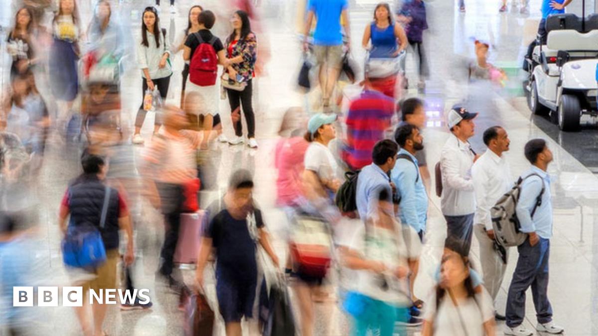 A blur of people move through a busy terminal at Hong Kong Chek Lap Kok International Airport