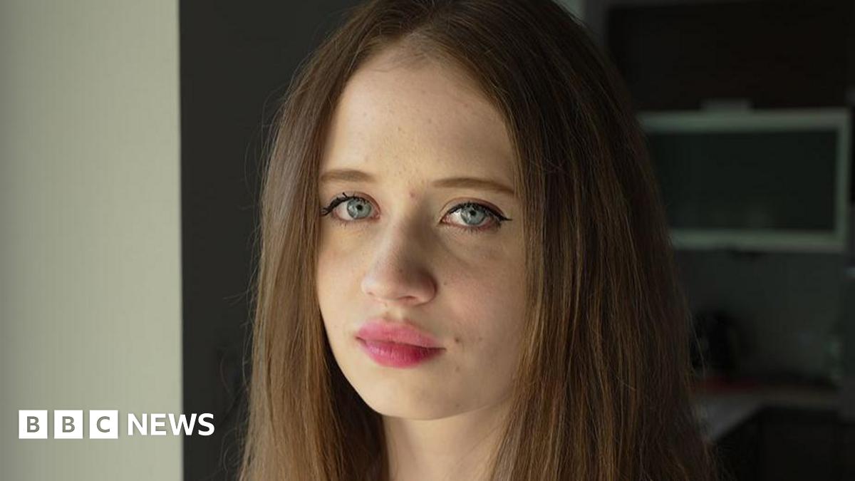 A portrait of Viktoria, a young woman with long, brown hair and blue eyes, pictured close-up and facing the camera