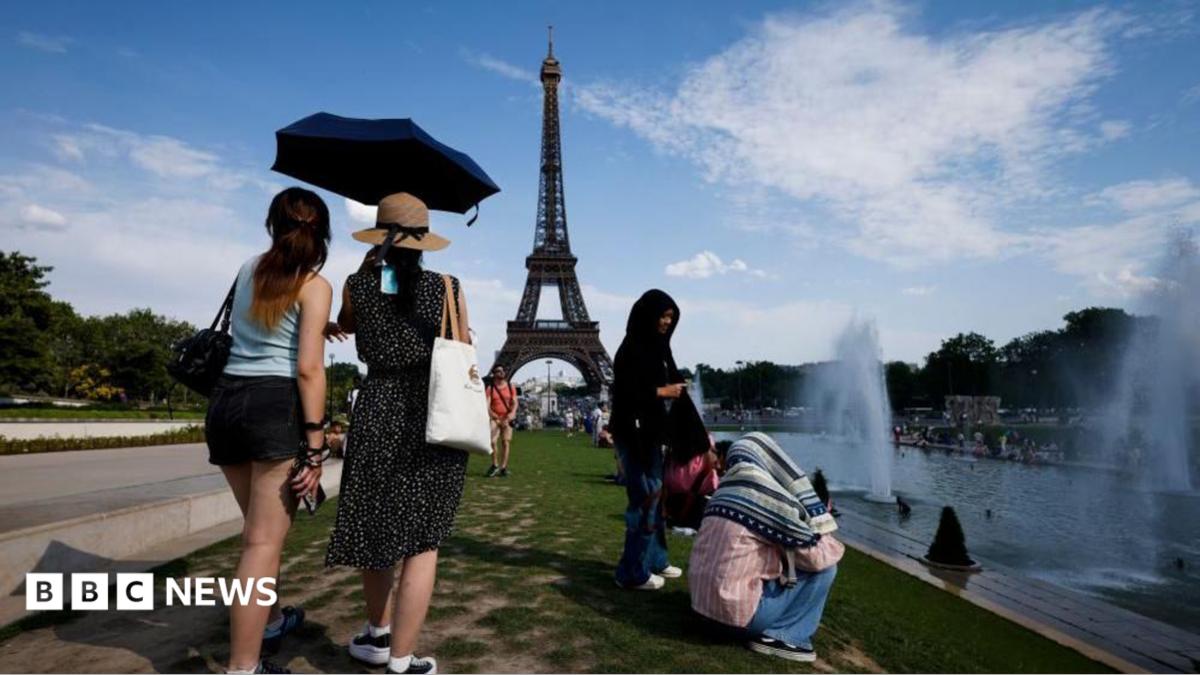 people under an umbrella because of the heat in paris with the Eiffel Tower in the background