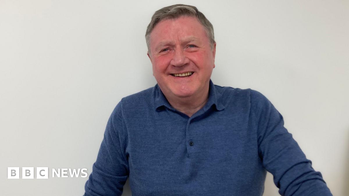 Dennis Jones wearing a blue long-sleeve T-shirt, smiling for camera.