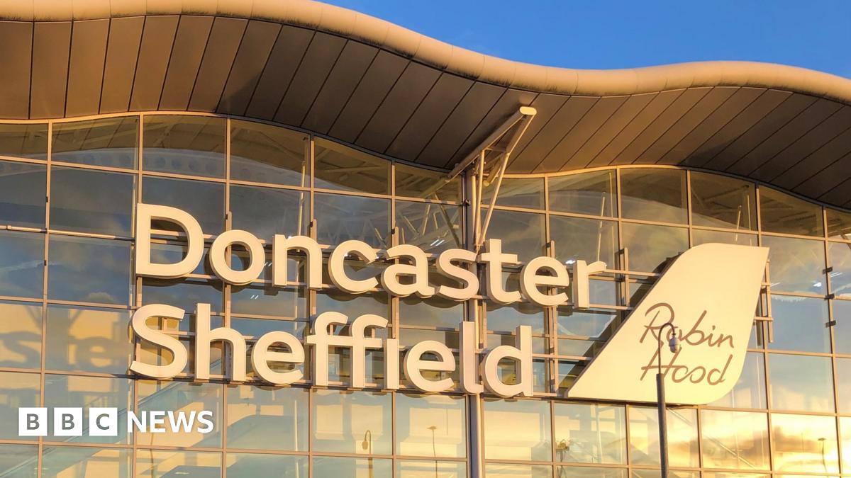 Doncaster Sheffield Airport's sign, made of large white letters on the glass building, taken at sunset.