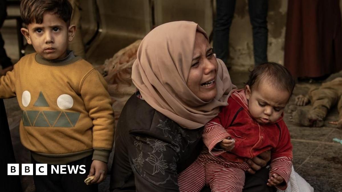 A Palestinian woman shows anguish as she holds a baby, with a boy standing next to them, in Gaza City (18/03/25)