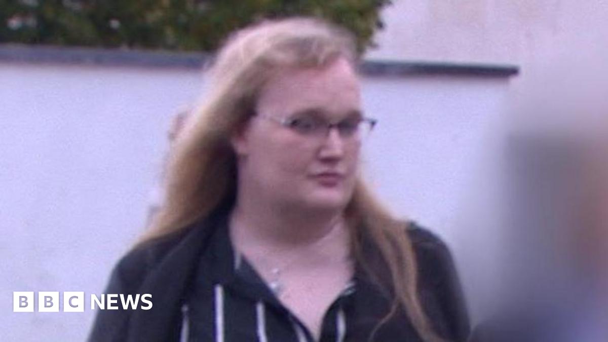 Rose Henderson arrives at the tribunal. Rose has long blonde hair, glasses and is wearing a black and white stripey dress.