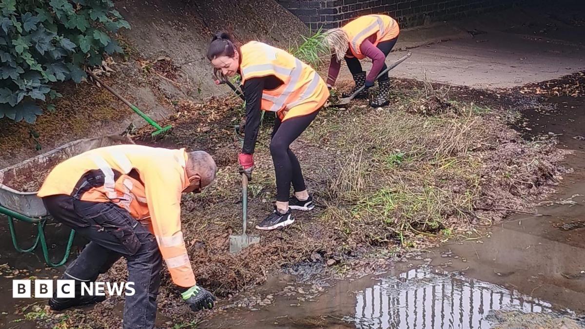 Photo: bbc.co.uk Volunteers in high viz on the floor of a river with almost no water lifting soil and silt