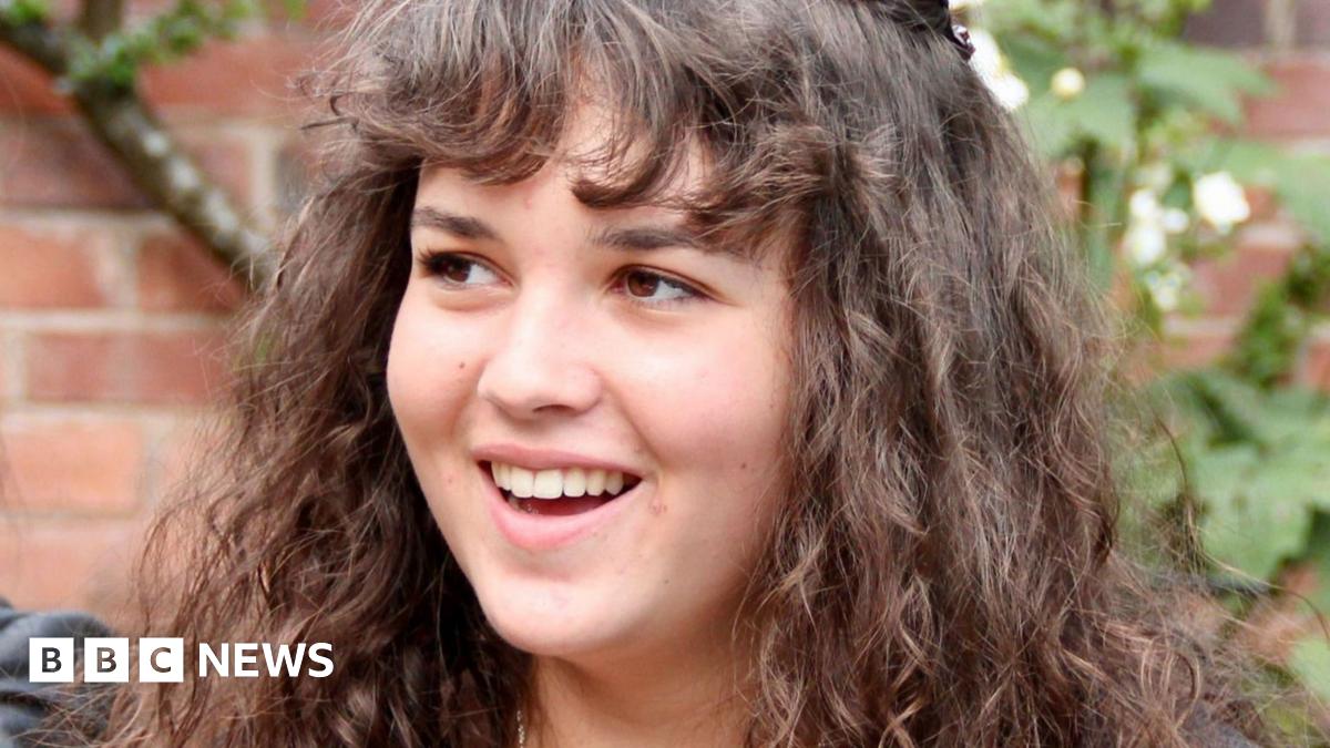 A photo of Maeve. She had brown, curly hair and a fringe covering her forehead, she is looking off to the left and smiling