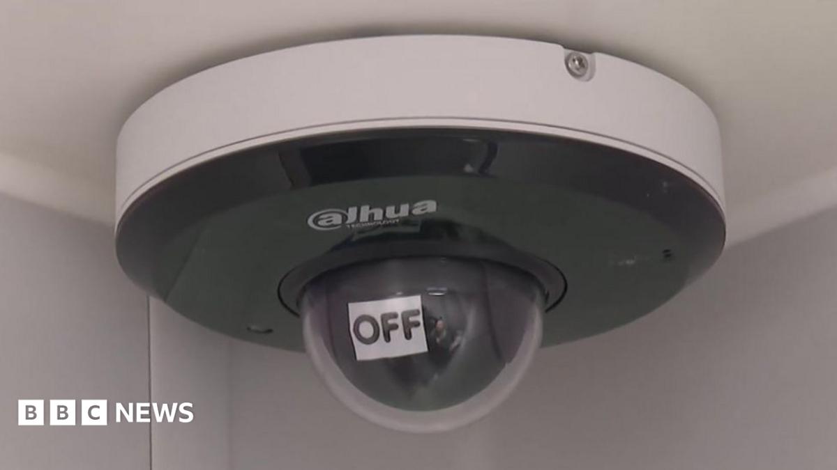 A ceiling-mounted internal CCTV camera. In front of its lens is an automatically movable sign that says "Off".
