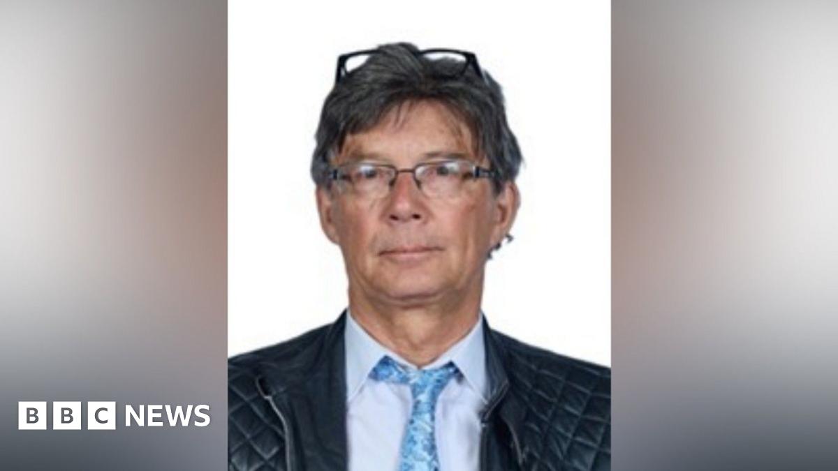 Barry Martin wears a blue tie and shirt and two pairs of glasses, one perched on top of his head. 