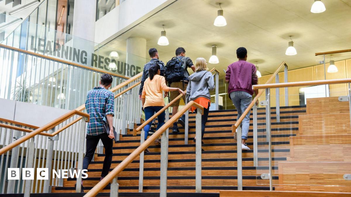 A group of six students walk up a set of stairs in a university building