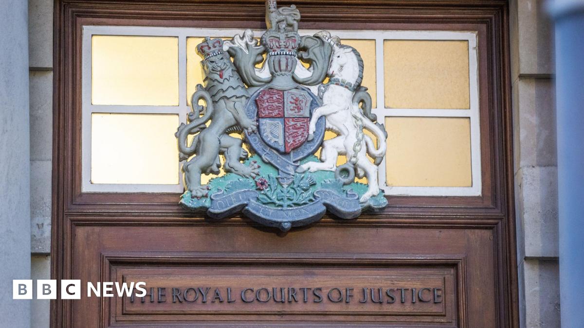 A brown door with an insignia. On the top of the door the words 'The Royal Courts of Justice'