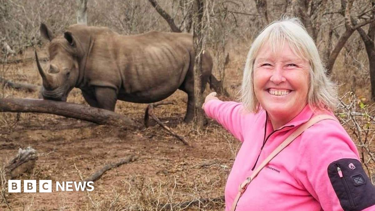 Lynn Stephenson wearing pink and pointing at a rhinoceros 