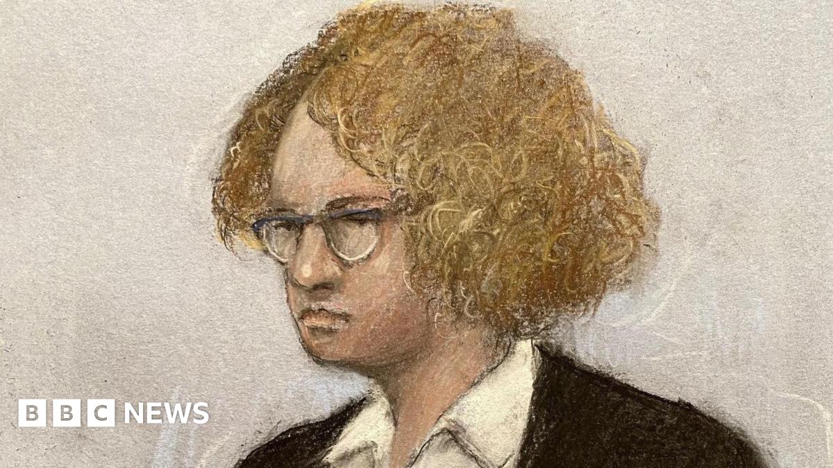 A sketch shows Gwyn Samuels standing in the dock, wearing a dark coloured jacket and a white shirt, with curly ginger hair and glasses. Next to her is a female security guard with tied-back hair and glasses.
