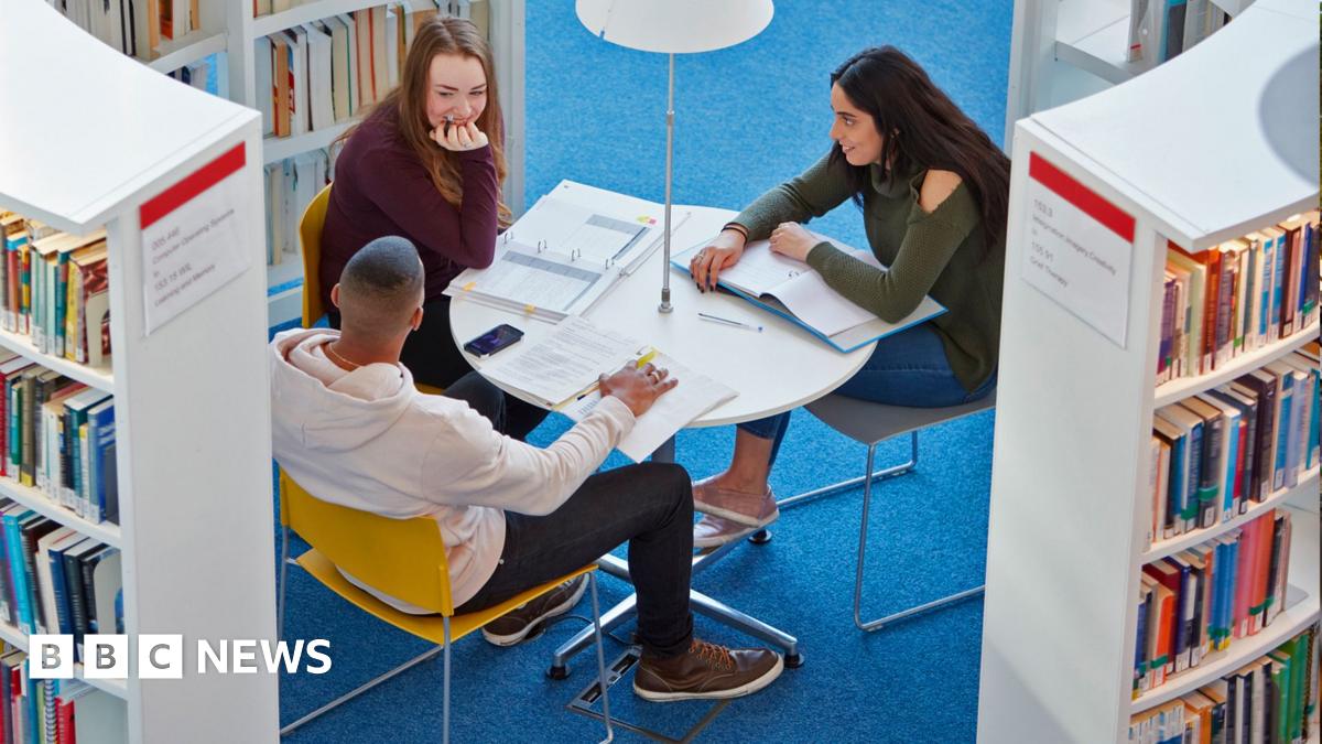 A diverse group of students sit at a table in a university library.