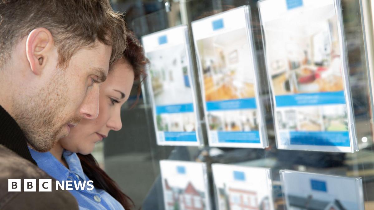 Young man and woman look in an estate agent's window 