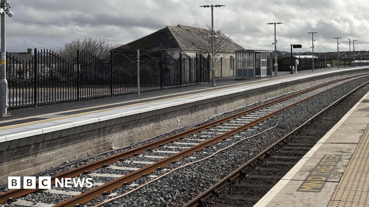 Newquay railway station's new track and platform heading off into the distance with a bus shelter and lighting on the platform 