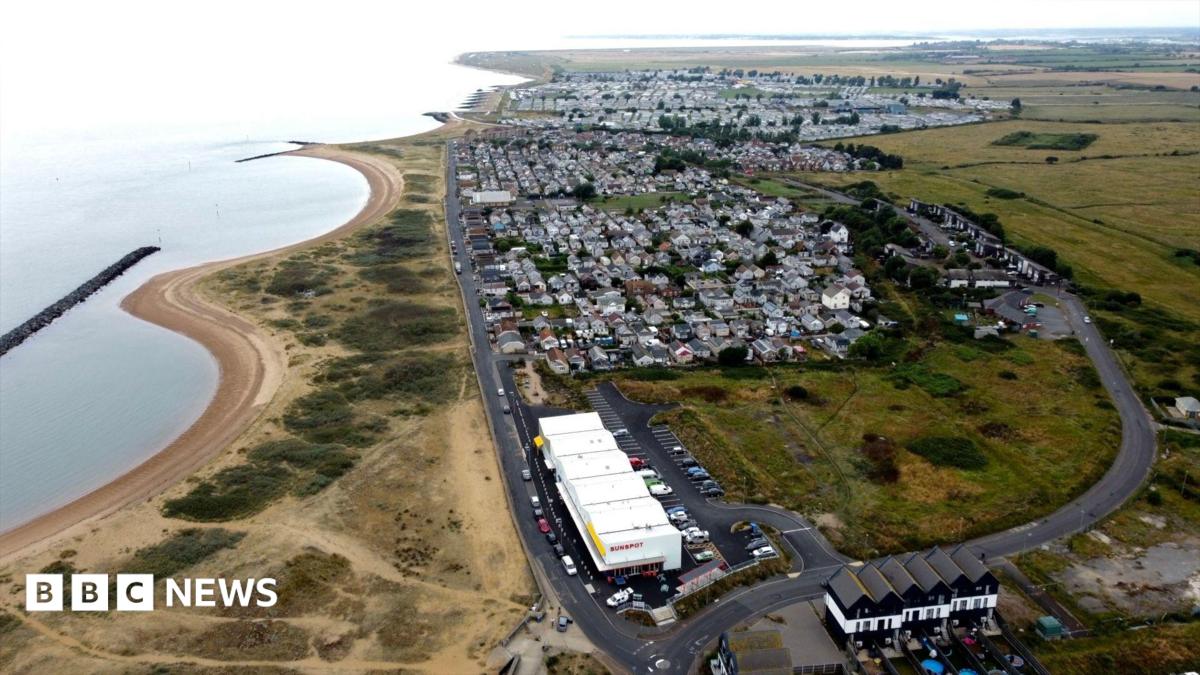 A bird's eye view of a seaside village with houses, the coast and the sea visible