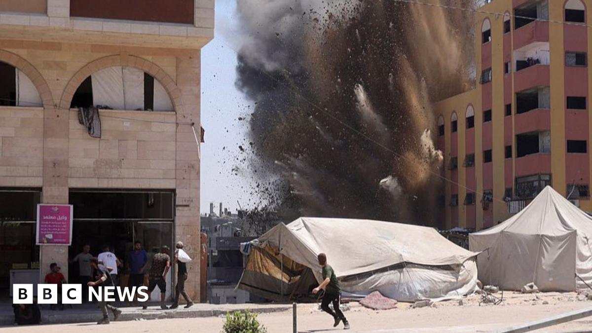 Palestinians rush for cover as smoke billows after an Israeli strike on a building in Jabalia in the northern Gaza Strip