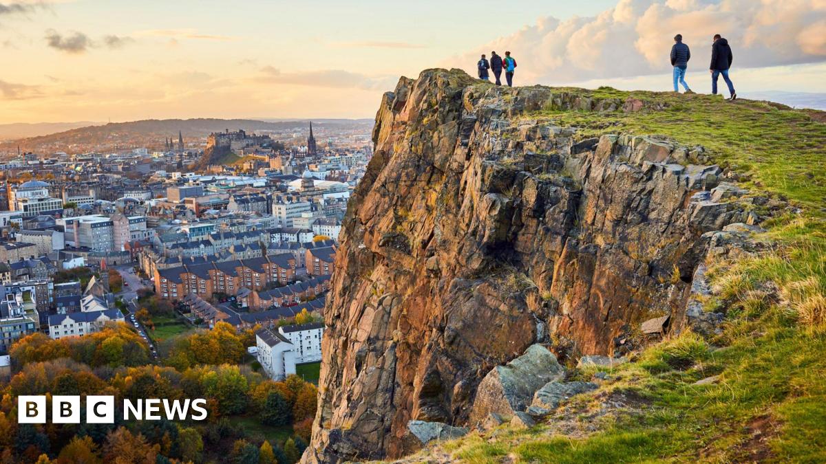 Five people on the edge of a cliff, looking over the centre of Edinburgh. The castle can be seen in the background. 