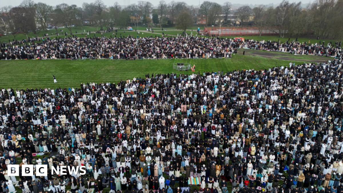 A drone view of Muslim men and women praying in a park.
