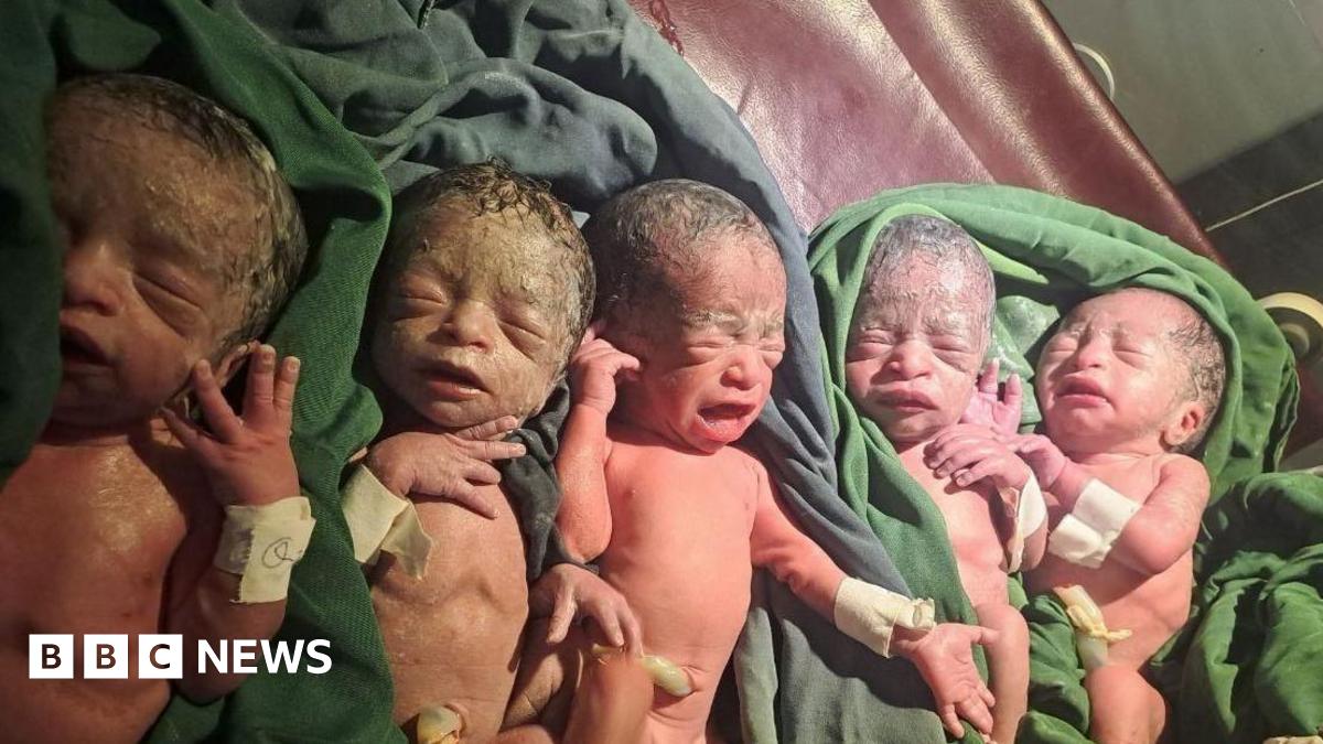 Five babies close up in hospital, placed on green sheets. They are still covered in residue from their births.