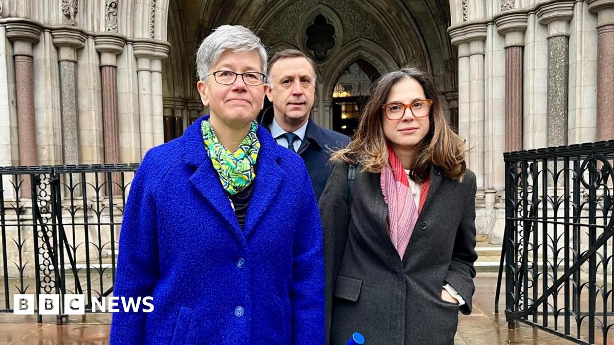 The Vice-Chancellor and President of the University of Sussex, Professor Sasha Roseneil, stands outside court in a bright blue coat. Next to her stand two senior university staff. 