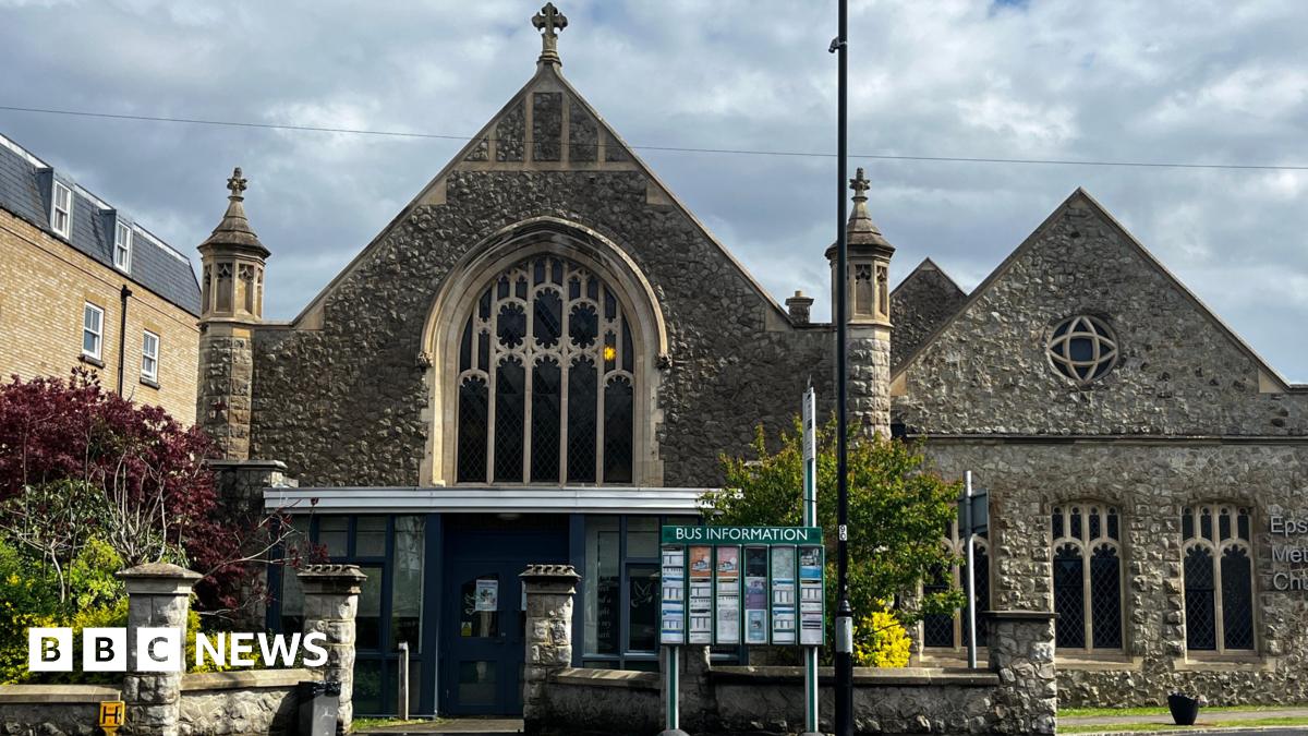 A church built with stone. There is a sign in front of the building.