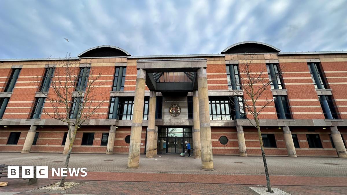 Exterior of Teesside Crown Court. It is a large imposing three-storey building made from red brick with long dark windows and four giant columns supporting a glass roof above the porch.