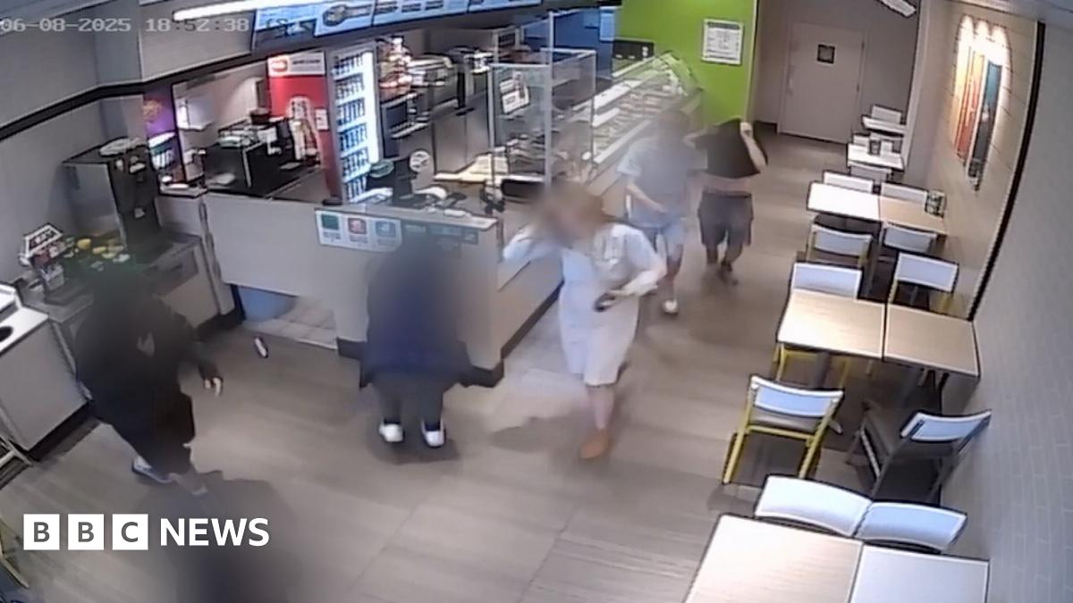 A group of teenagers, blurred, run amok in a shop as they carry out antisocial behaviour, as seen from a CCTV camera at a high angle.
