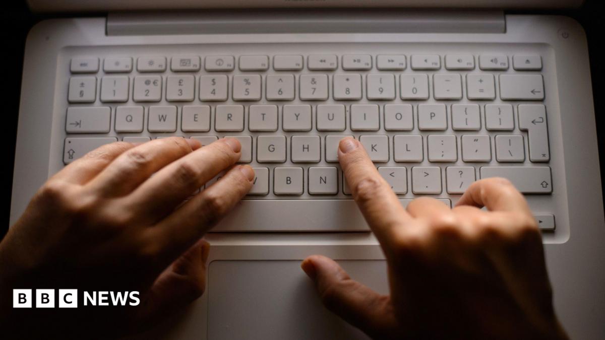 Close-up of a laptop computer keyboard, with woman's hands typing on a MacBook. Two hands are typing on the QWERTY keyboard.