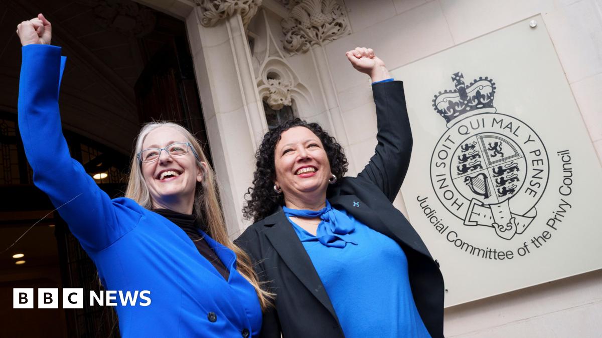 Campaigners Helen Joyce (left) and Maya Forstater (right) celebrate outside the UK Supreme Court in London. Helen has long blonde hair and glasses and is wearing a blue jacket and black top. Maya has curly dark hair and wears a blue blouse and black bl...