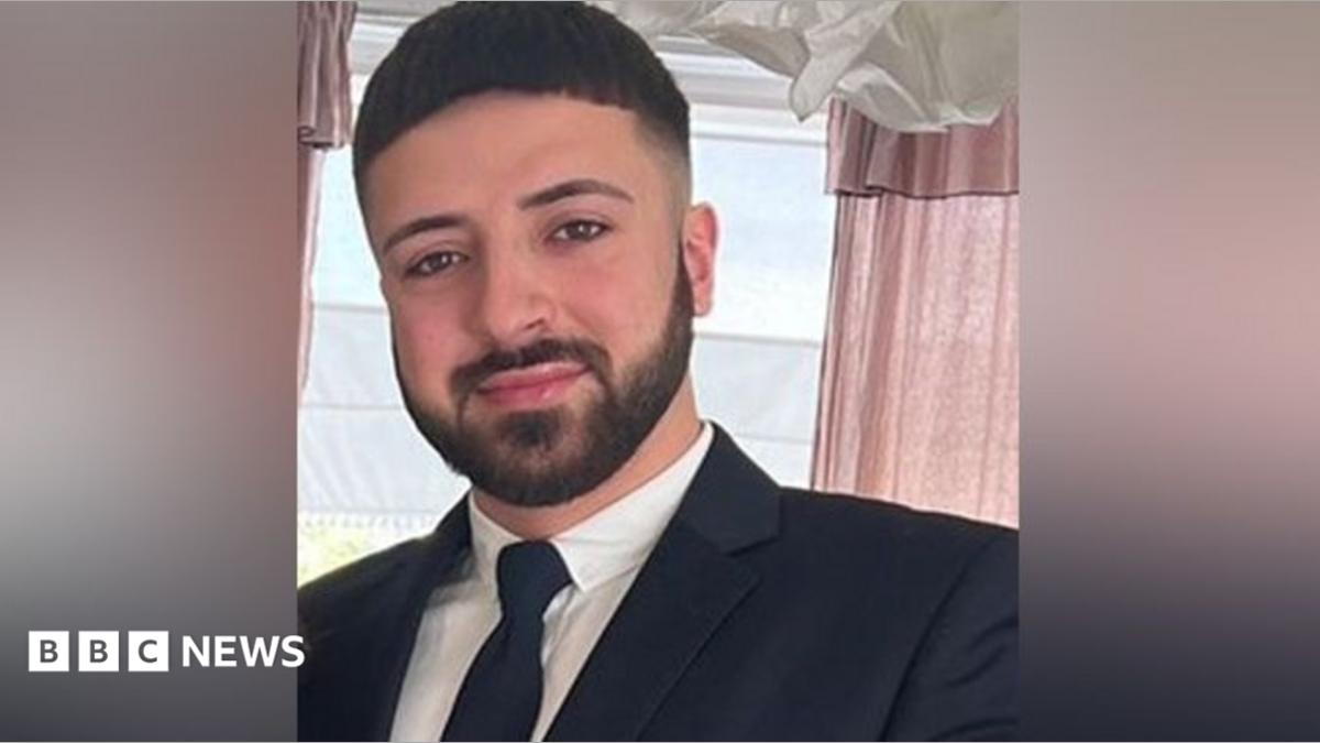 Kyle Clifford dressed in a dark suit and tie, with a beard and brown eyes 