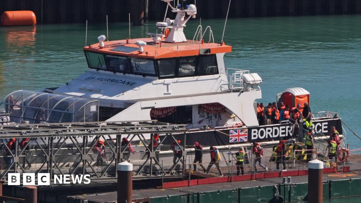 A group of people wearing life jackets being brought off a Border Force vessel at Dover 