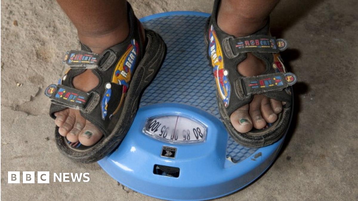 An six-year-old Indian child measures his weight
