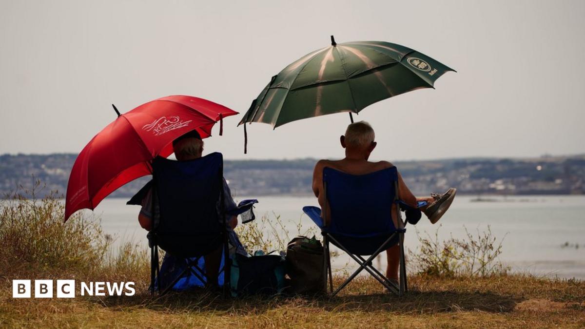 People sheltering under umbrellas from the sun in St Michael's Bay in Cornwall. Temperatures are predicted to hit 31C across central England on Sunday ahead of record-breaking highs next week. Picture date: Sunday July 17, 2022.