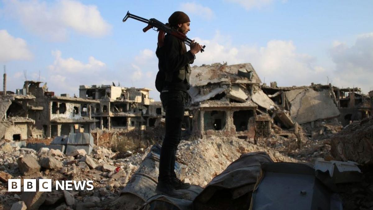 A rebel fighter stands amid the rubble of destroyed buildings in a rebel-held area of Deraa, in southern Syria, on 14 March 2017