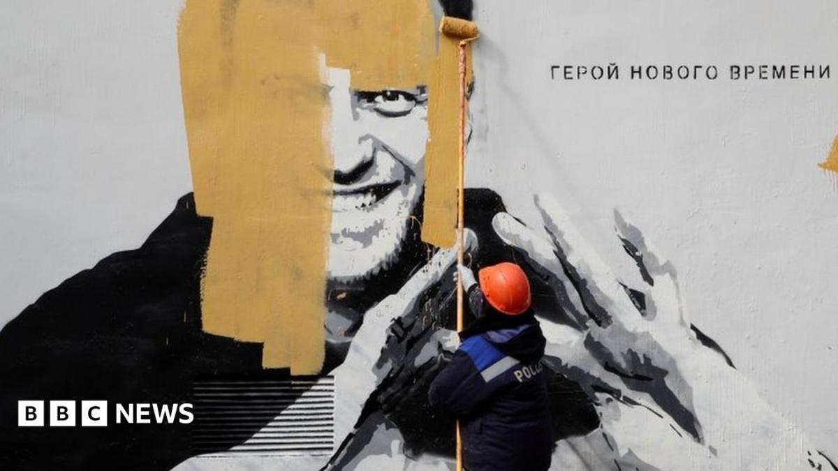 A worker paints over a graffiti depicting jailed Russian opposition politician Alexei Navalny in Saint Petersburg