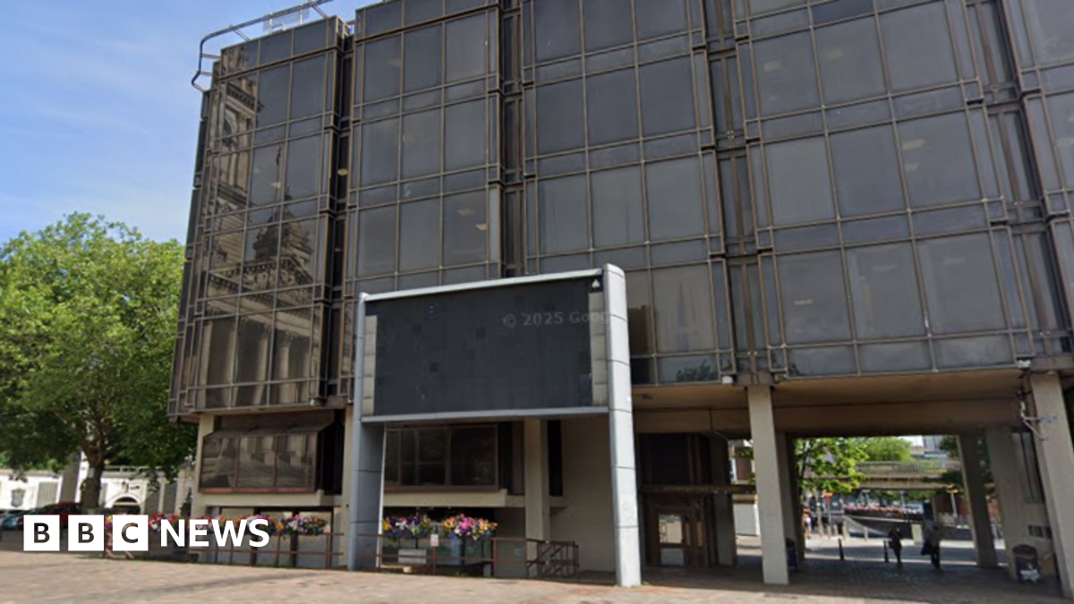 A five-storey, glass-fronted office building in a pedestrianised square.