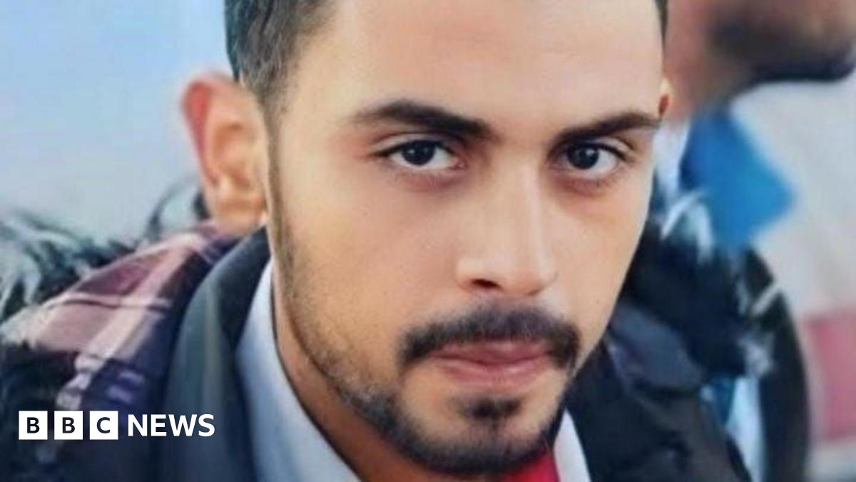 Close-up photo of Rifaat Radwan. He is looking at the camera, has black eyes and black beard. He is wearing a light blue shirt and a dark blue jacket.
