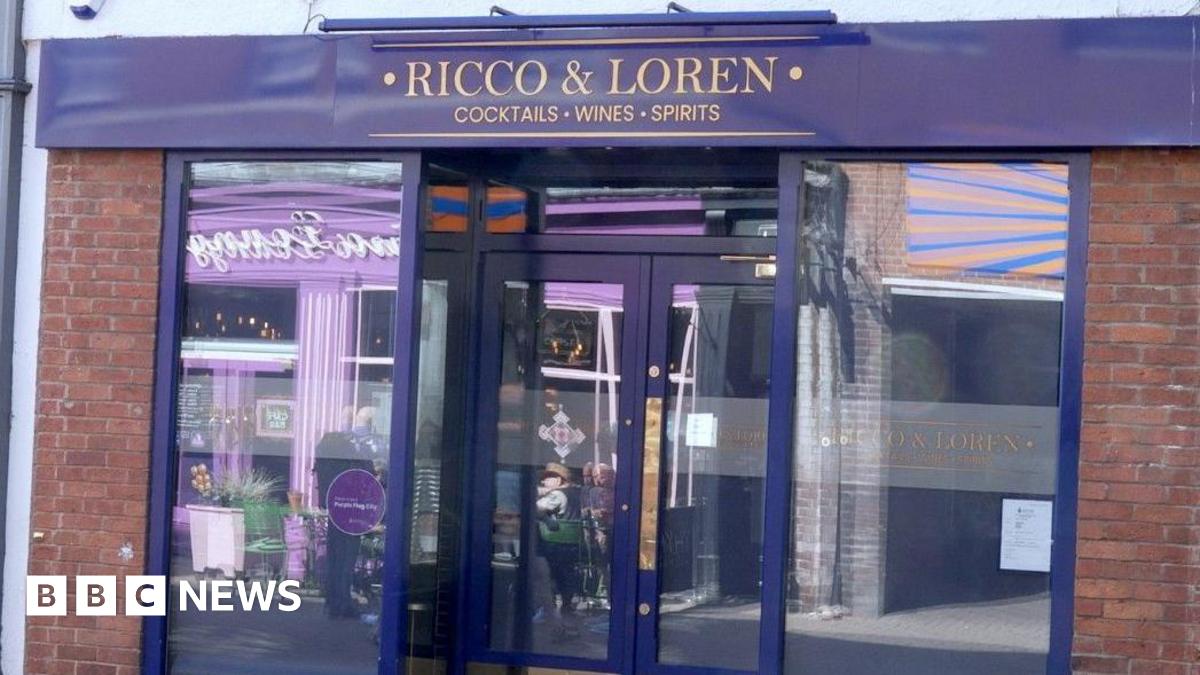 A shiny blue shop front with Ricco & Loren, cocktails wines sprits written in gold at the top of the doors.