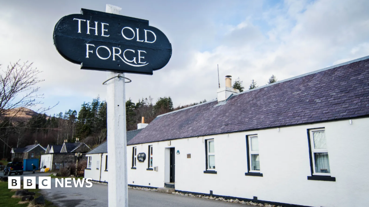 A long white building with a large sign reading The Old Forge in front