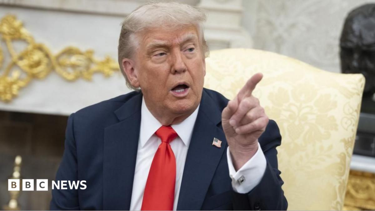 Donald Trump points while sitting in the Oval Office.