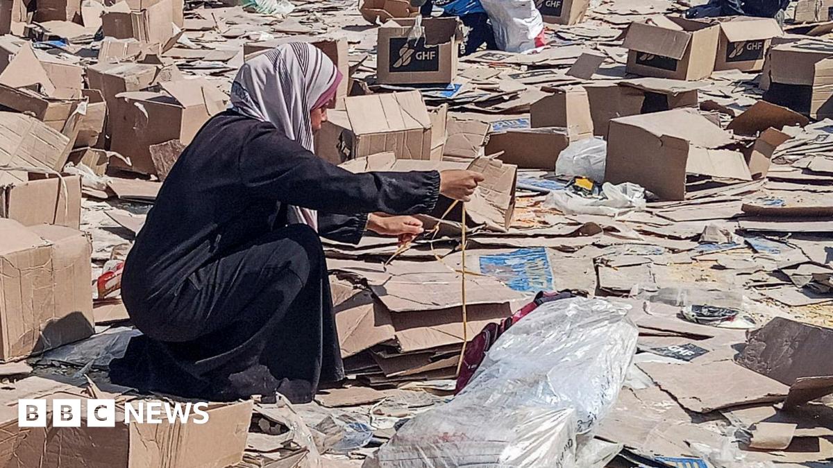 A woman pictured picking through broken cardboard boxes on the ground