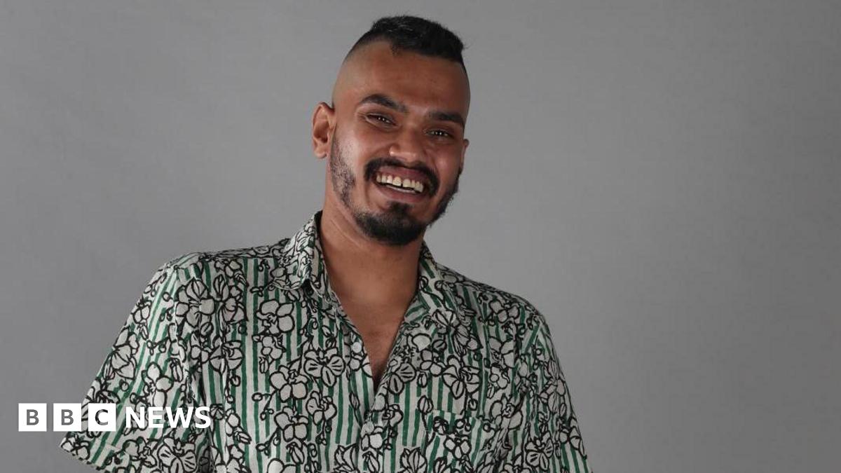 Mohaimen with a big smile looking at the camera, wearing a cotton printed shirt which is both striped and has flower images on it.